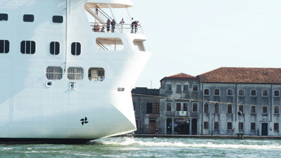 A cruise ship moves close to old homes along a Venetian canal.