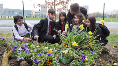 Group of school children gathered around plants.