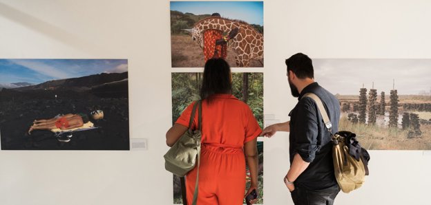 Two people looking at photographs on a wall.