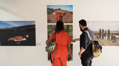 Two people looking at photographs on a wall.
