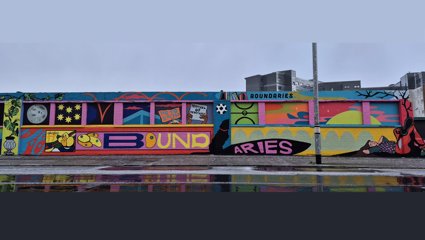Colorful mural on a city wall featuring the word 'BOUNDARIES' with vibrant geometric shapes.