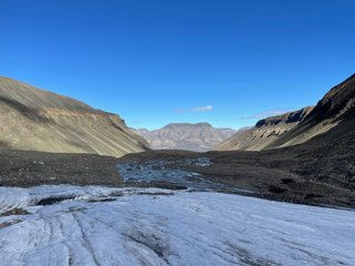 The edge of a glacier and meltwater in the base of a u-shaped valley.