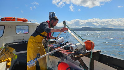 Someone in yellow overalls inspects equipment on a boat in Scotland