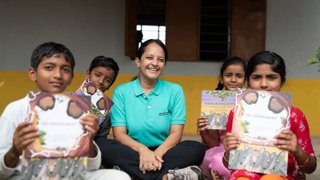 Dr Krithi Karanth and four pupils holding up books.