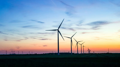 Wind turbines in shadow with sunset background.