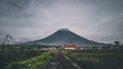 Houses situated in front of a smoking volcano