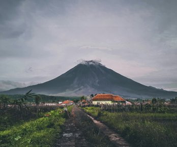 Houses situated in front of a smoking volcano