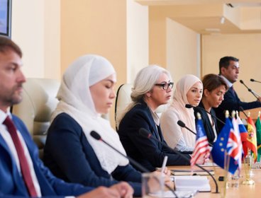 People at conference table with flags.