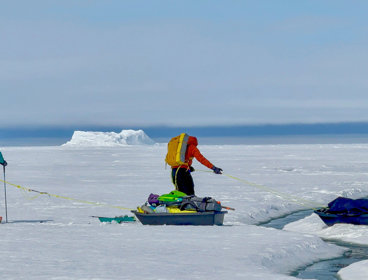 Two researchers pulling sleds on a large ice sheet.