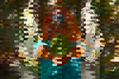 A woman hodling a green leaf out to the camera