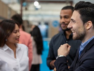 Four people in offce clothing networking in a formal setting.
