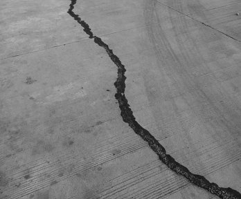 Greyscale photo of crack in concrete