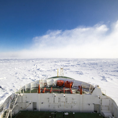 Looking out to the front of the SA Agulhas II ship sailing through the ocean in Antarctica, with pack ice all around