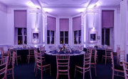 Round dinner tables set-up in the Education Centre with purple uplighters. 