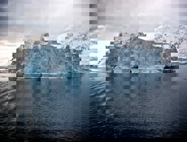 White iceberg near white mountains in Antarctica