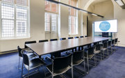 A small meeting room with a boardroom style set-up. 