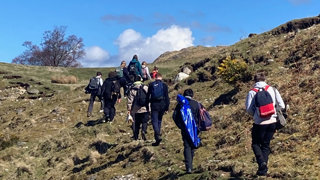 People walking up a hill as part of their geography fieldwork.