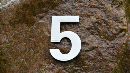 A white number 5 on a brown rock background