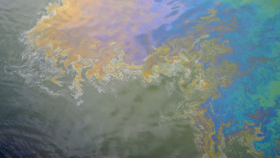 Oil spill on water. Photograph title 'Toxic Oil Surface'.