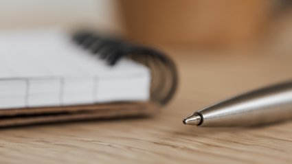 Open notebook and ballpoint pen on a table. 