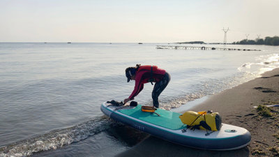 Person setting up a paddle board on a beach.