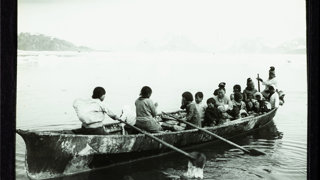 Old photograph of a group of people rowing a boat.
