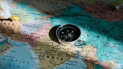 A modern compass laying on top of a world map.