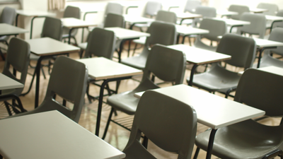 Clasroom filled with rows of desks and empty chairs.