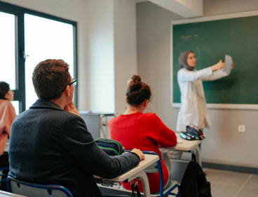 Three students in a university class listen to the teacher 