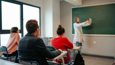 Three students in a university class listen to the teacher