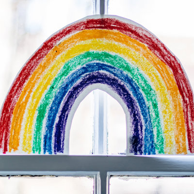 A drawn image of a rainbow, placed in a window.