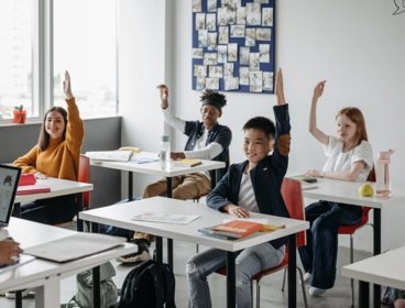 Classroom of kids raising their hand to teacher.