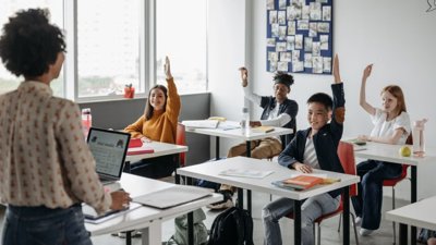 Classroom of kids raising their hand to teacher.