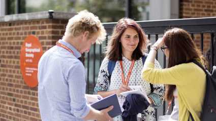 Three people having a conversation outside the entrance of the Royal Geographical Society in London.