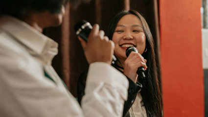 Two people on a stage talking, both are holding microphones.