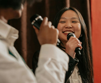 Two people on a stage talking, both are holding microphones.