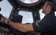 Astronaut in space looking at Earth from inside a space station.