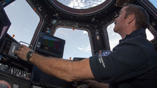 Astronaut in space looking at Earth from inside a space station.