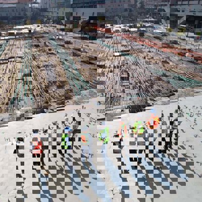 A group of people in high vis jackets standing on a roof top overlooking a building site