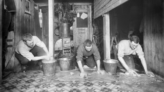Historical black and white photograph of the crew washing the floor of the Endurance.