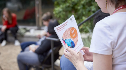 A person reading a conference programme.