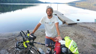James Peach standing with bike in front of a lake