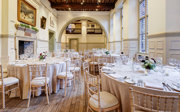 Round dinner tables with neutral linen set-up in a grand main hall for a wedding. 