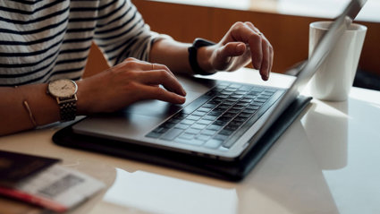 Person seated at the table using laptop.