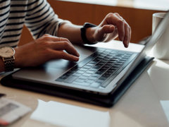 Person seated at the table using laptop.