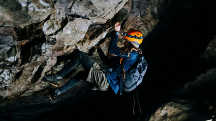 A woman who is rock climbing inside a cave.