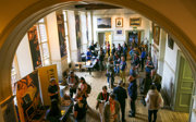 A large gathering of people networking in a stately main hall, as seen from above.