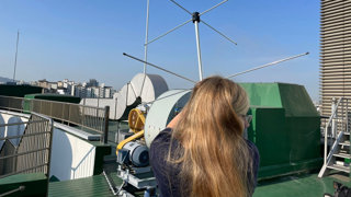 Madelaine Joyce conducting fieldwork in South Korea, holding a large antenna to carry out satellite records and image the weather systems.
