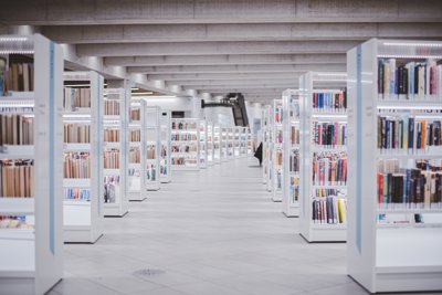 White book shelfs, neatly stacked with books fill the light grey interior of a minimalist library