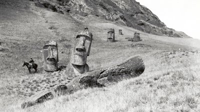 General view of the statues standing within the southern outer slopes of the statue quarry Rano Raraku (Horse and rider for scale), Easter Island, 1913. 